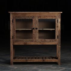 an old wooden cabinet with glass doors on the front and bottom shelves, against a dark background