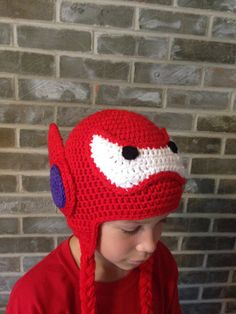 a young boy wearing a crocheted red hat with an angry bird on it