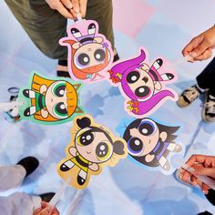 several people holding up cartoon stickers in the middle of a circle with their hands