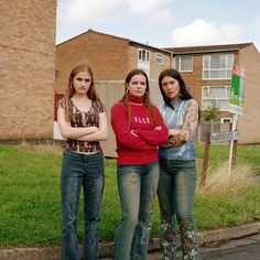 three girls standing in the street with their arms crossed