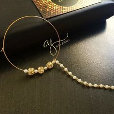 a close up of a pair of earrings on a table with a book in the background