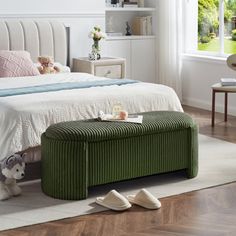 a bedroom with a large bed and green foot stools on the hardwood flooring