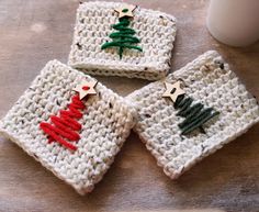 four crocheted coasters with christmas trees on them and a mug in the background