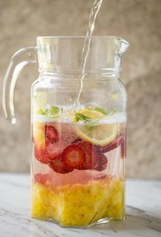 a glass pitcher filled with fruit and water