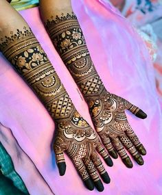 two hands with henna tattoos on them