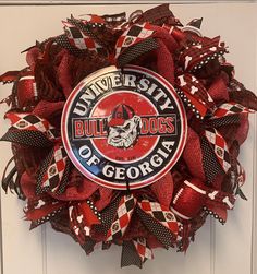 Show your team spirit with this delightful, cheerful, one-of-a-kind wreath for football season.  This lovely wreath is made of poly burlap mesh, which is waterproof, thicker, and has a more substantial hold and body than other types of mesh.  This very thick and FULL wreath is crafted on a 15-inch wired, elevated, work wreath form. The meshes are a 21" Red Poly Burlap Check Mesh and an awesome, quality, 10" Red/Black Check Poly Burlap Mesh. The 10" Poly Burlap Mesh compliments the 21" Red Poly Burlap Mesh, giving the wreath a great Georgia Bulldogs feel! There are 4 different ribbons containing tones of black, red and white that come together to compliment the mesh. The 2.5" and 1.5" ribbons are incorporated into the wreath through ribbon tails. Rounding out the wreath is an awesome round Georgia Bulldog Wreath, Uga Football, Go Dawgs, College Football Season, Work Wreath Forms, Work Wreath, Festive Wreath, University Of Georgia, Wreath Forms