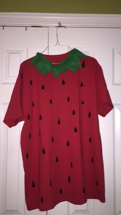 a red shirt with watermelon print on it hanging from a hook in front of a door