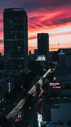 the city skyline is lit up at night with bright lights and traffic on the street