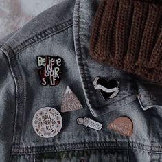 a denim jacket with patches and pins on it, including a beanie hat that says believe our star