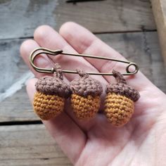 small crocheted acorns hanging from a hook in someone's hand