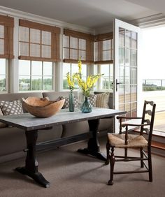 a living room filled with furniture and flowers on top of a wooden table next to a window