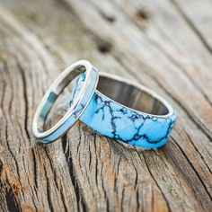 two wedding rings sitting on top of an old wooden table with blue and white marble inlays