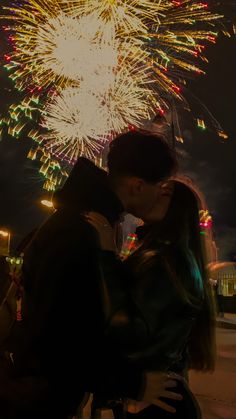 a man and woman kissing in front of fireworks