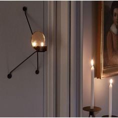 candles are lit in front of a painting on the wall next to a candle holder