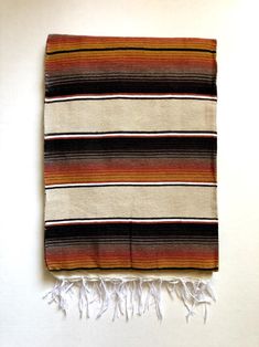 a striped blanket with fringes hanging on the wall