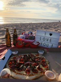 a pizza sitting on top of a table next to beer bottles and an i love you sign