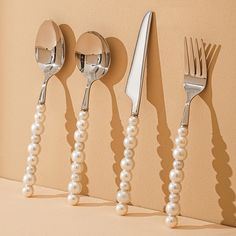 four forks, two spoons and one knife with pearls on them