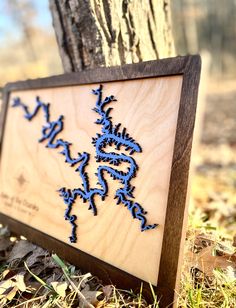 a wooden sign sitting next to a tree in the grass