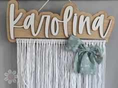 a wooden sign that says karofina hanging on a wall with a bow