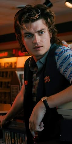 a young man leaning on a counter in a restaurant looking at the camera with an intense look