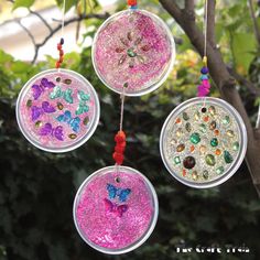 three glass ornaments hanging from a tree branch with beads and crystals in the shape of butterflies