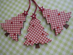 three red and white christmas trees hanging on a green checkered tablecloth covered table