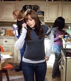 a woman standing in a kitchen talking on a cell phone