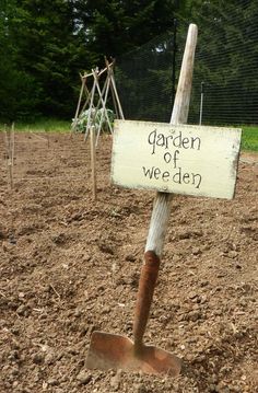 a garden sign in the middle of a dirt field