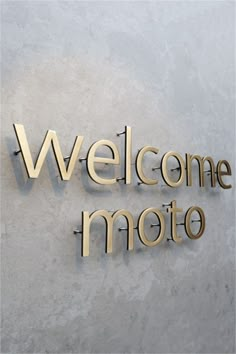 the welcome sign to moto is made out of wood and has gold lettering on it