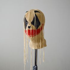 a head made out of rope with a face painted on the side and fringes hanging from it