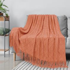 a living room with a gray couch and orange blanket