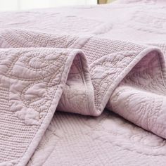 an unmade bed with a pink quilt on it