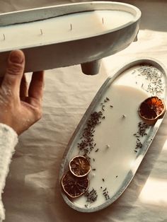 a tray with dried herbs on it next to a person's hand holding an object