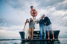 a group of people standing on top of a boat in the water with a man hanging from it's side