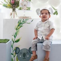 a little boy sitting on top of a white box with a koala wallpaper