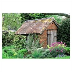 an old outhouse surrounded by flowers and trees