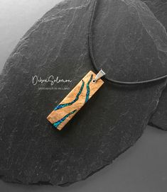 a wooden pendant with blue beads on a black stone background and the words,'i am