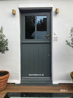 a grey front door with two potted plants