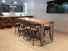 a bar with several stools in the middle of it and a television mounted on the wall