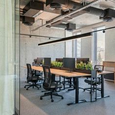 an empty conference room with desks and plants in the center, along with other office furniture