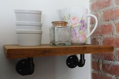 there are cups and mugs on the shelf next to each other in front of a brick wall