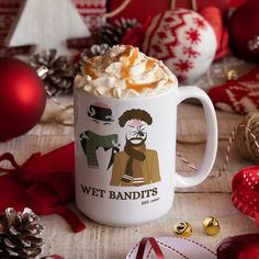 a white coffee mug with hot chocolate and whipped cream on top, surrounded by christmas decorations