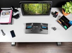 a desk with a computer monitor, keyboard and other office supplies on top of it