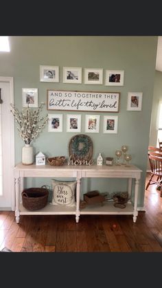 a white table with pictures on the wall above it and other items sitting on top of it