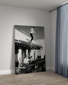 a black and white photo of a man on a snowboard jumping over a roof