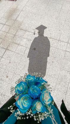 the shadow of a person standing next to a bouquet of flowers on the ground with a man's shadow in the background