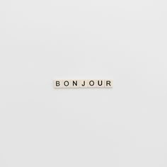 the word bonjou spelled with scrabble letters in black and white on a plain background