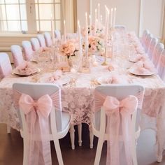 the table is set with pink and white flowers, candles, and napkins on it