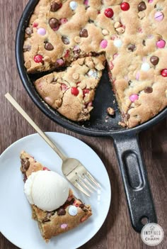 a chocolate chip cookie cake with ice cream on a white plate next to a cast iron skillet