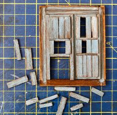 an old window with broken wooden pieces on the floor next to it and blue tiles